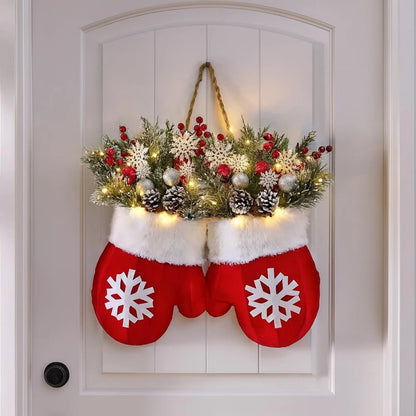 Glove-shaped red mitten garland on a door, featuring a snowy pine wreath with berries, pinecones and warm lights.